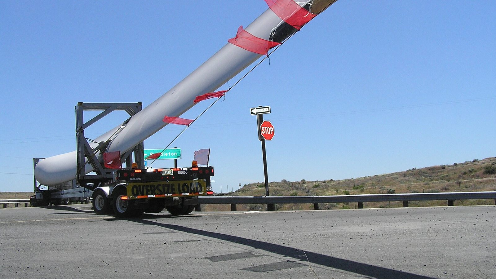 Un camion transporte une pale d'éolienne surdimensionnée sur une route.